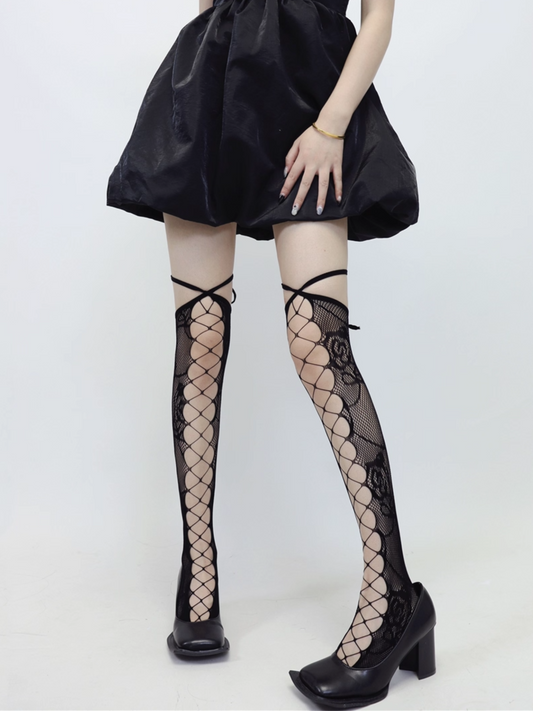 Person wearing black fishnet stockings with a plain background