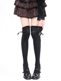 Black knee-high socks with ruffled top worn with a leopard print skirt on a white background