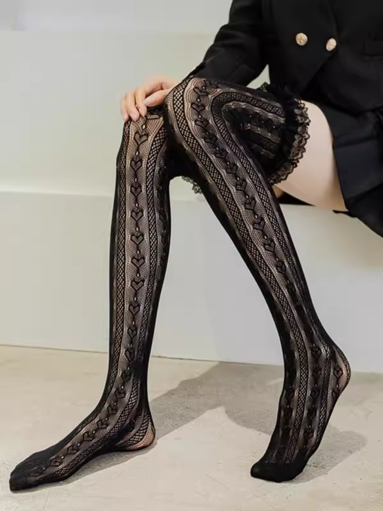 Black lace thigh-high stockings worn with a black outfit.