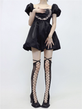 Person wearing a black dress with puffed sleeves and fishnet stockings on a white background