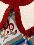 Close-up of a red knit sweater with a patterned fabric underneath