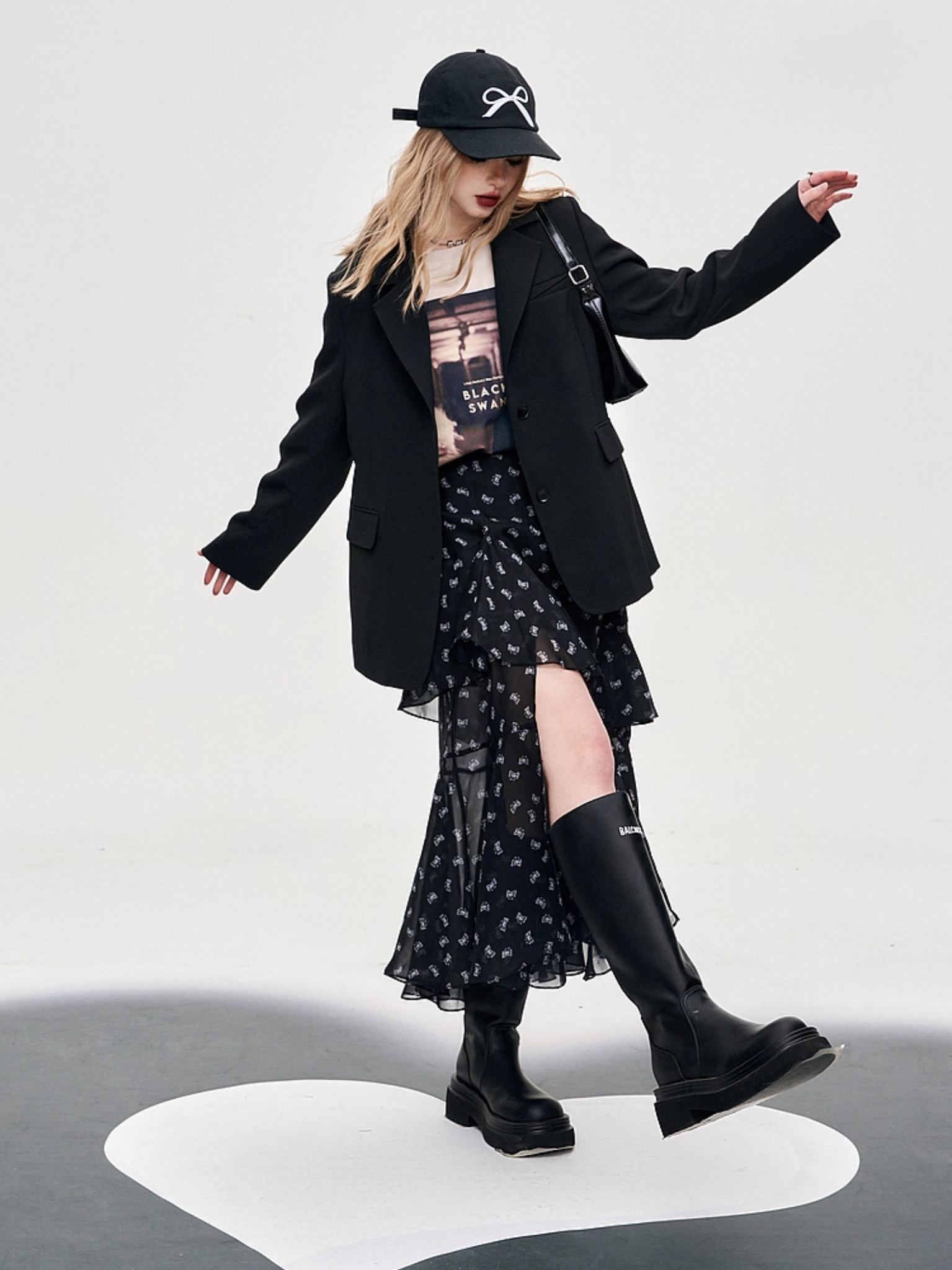 Person wearing a black outfit with a skirt and boots on a white background