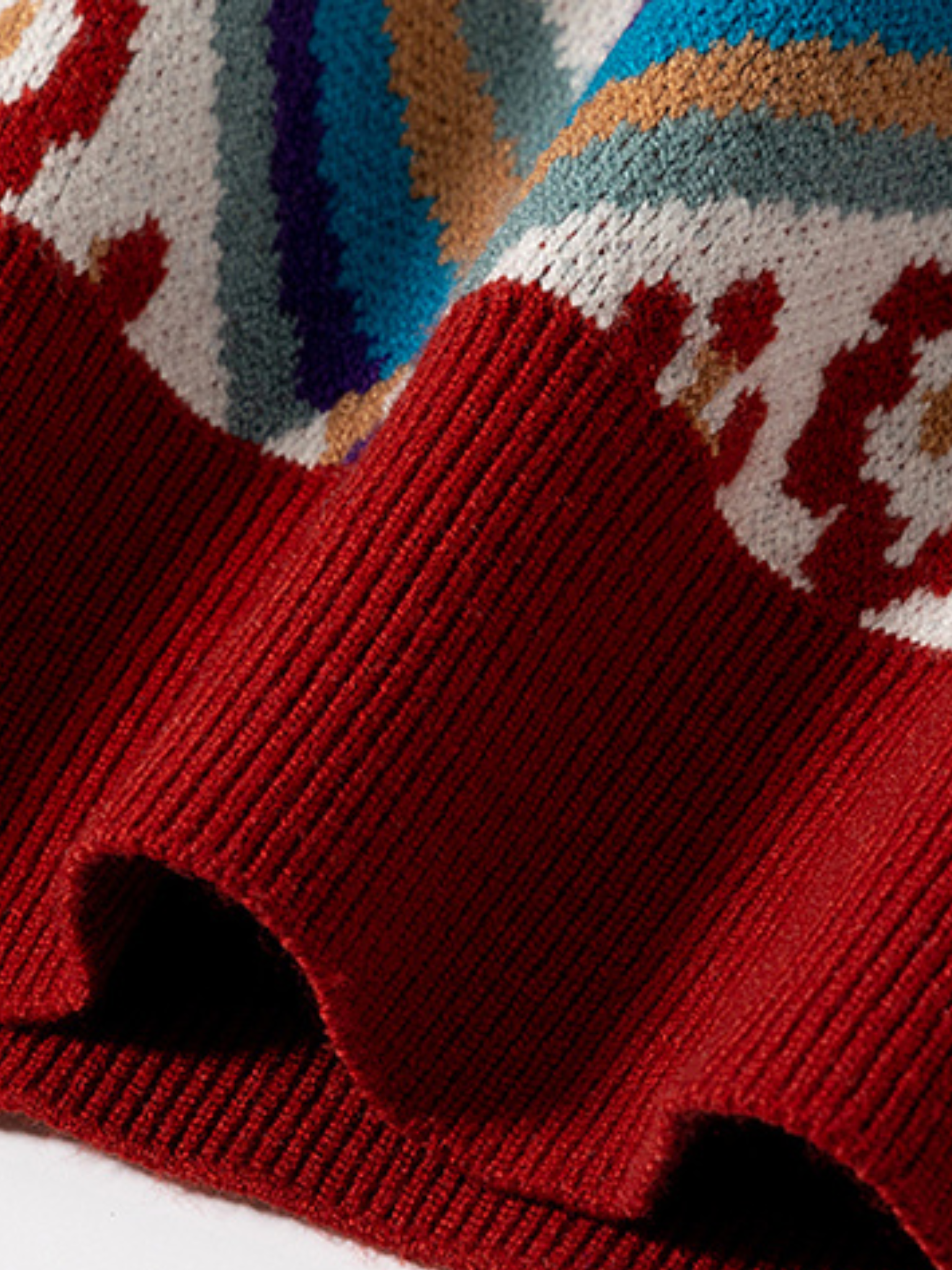 Close-up of a red knitted sweater with a colorful pattern on a white background
