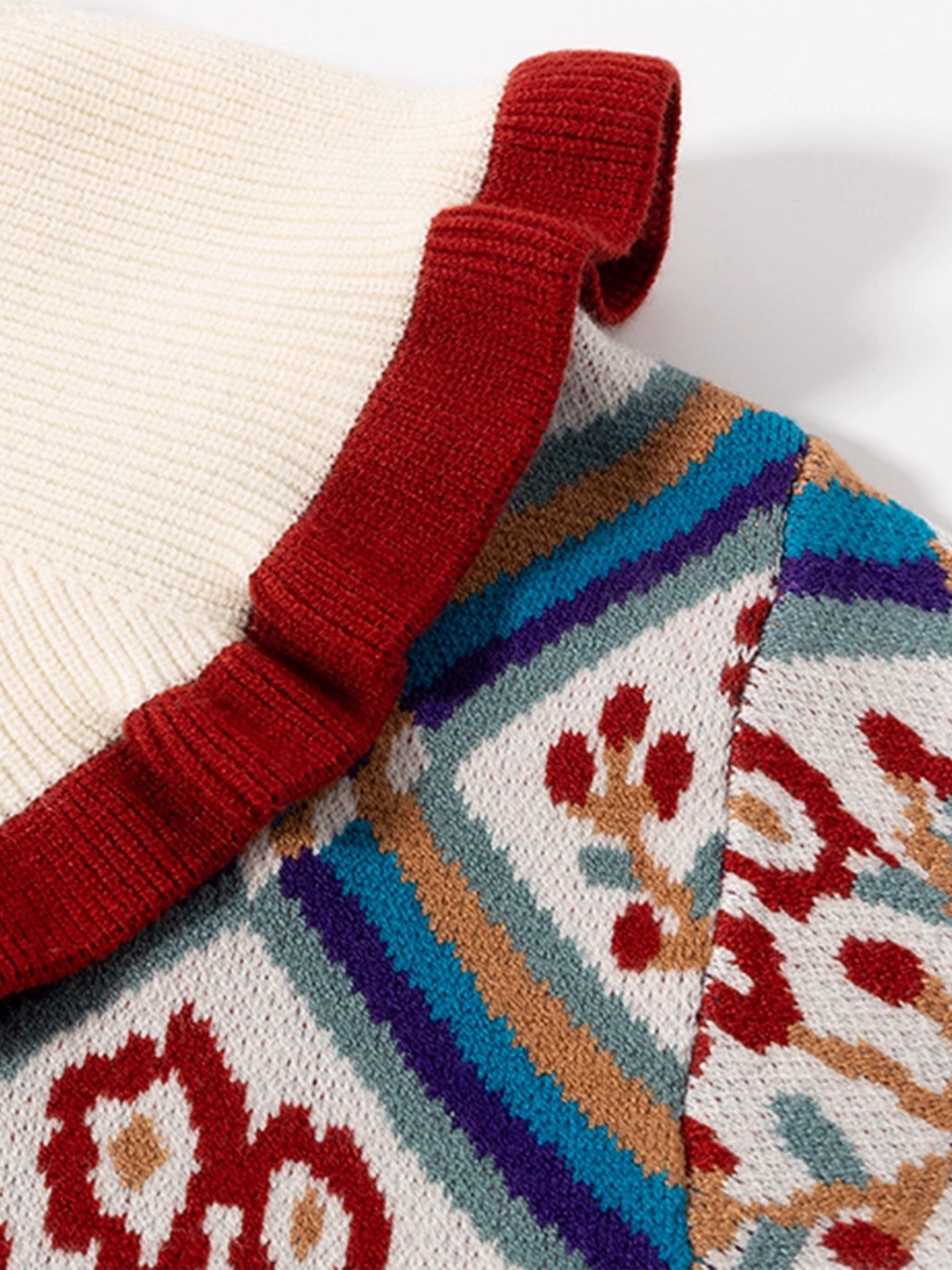 Close-up of a knitted garment with a colorful pattern and red strap.