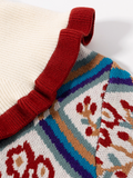 Close-up of a knitted garment with a colorful pattern and red strap.